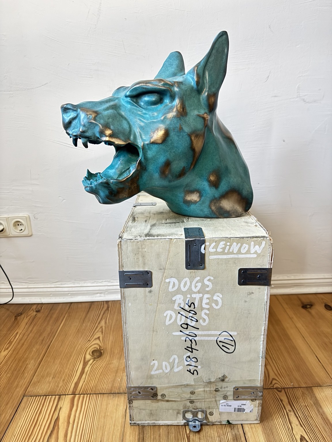 Dog bites dog — turquoise and gold dog sculpture on a wooden crate